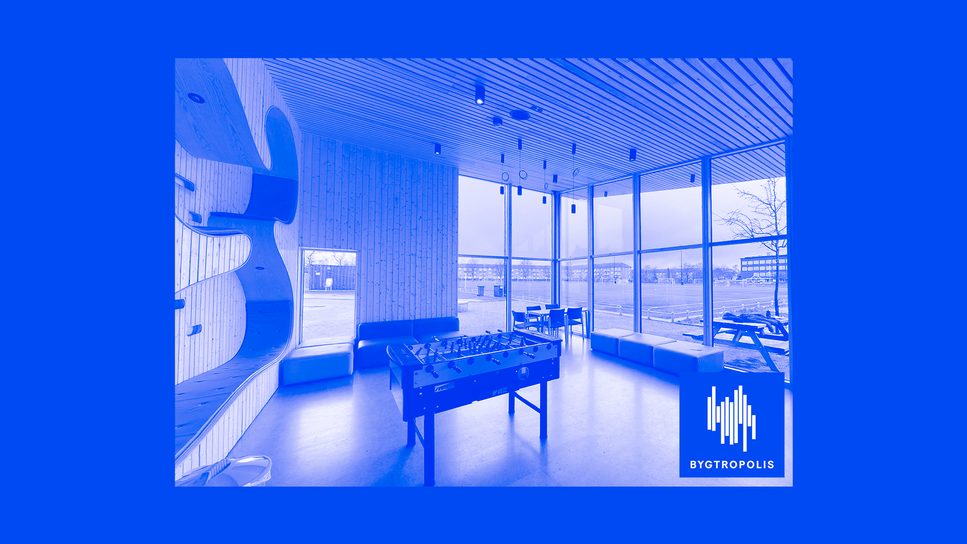 Et lyst lokale med store vinduer og et bordfodboldspil i midten. Billedet er tonet blåt.